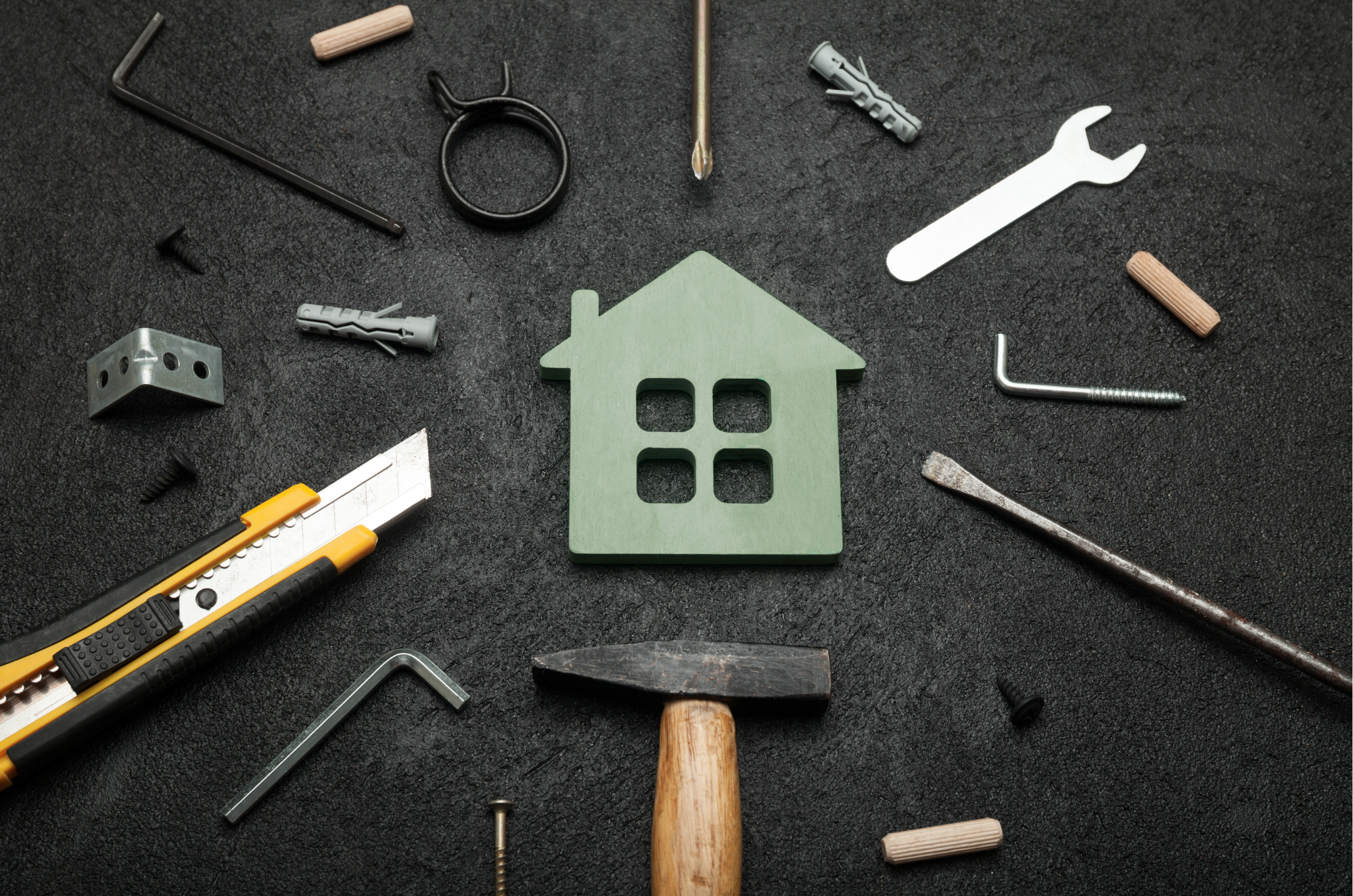 tools surrounding a toy home with black background